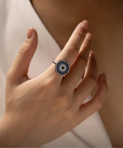 Macro shot of micro-pave evil eye ring with blue and black stones on hand