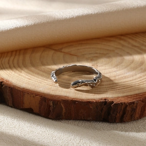 Detailed close-up of a silver irregular rock texture ring on a natural silk background