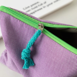 Detail von grünem Reißverschluss mit blauem Web-Puller an lila karierter Tasche
