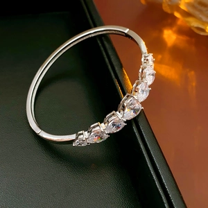Détail d'un bracelet ouvert argenté orné de zircons en forme de poire avec serti à griffes