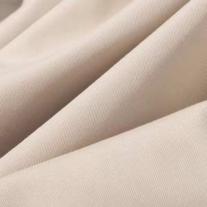 Close-up detail of the beige twill fabric texture on a cropped trench coat jacket