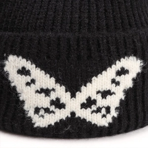 Winter knitted beanie with white butterfly jacquard pattern in thick black ribbed fabric