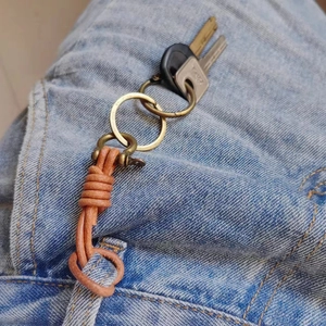 Handmade brown leather keychain with brass D-ring clasp on blue jeans loop