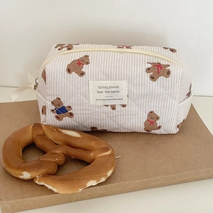 Close-up of bear-patterned quilted makeup bag with vertical stripes and zipper closure