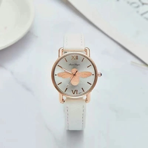 Women's quartz watch with gold bee dial and white leather strap on marble surface