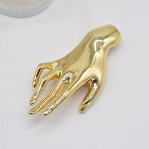 Detailed view of the gold metallic palm-shaped brooch showing glossy polished finish
