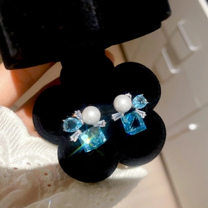 Macro shot of geometric square blue gemstone earrings with pearls in a black velvet box