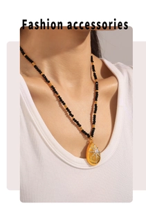 Close-up of beaded necklace with gold starburst pendant featuring sea shell texture