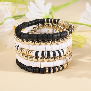 Detail of bohemian layered elastic heishi bead bracelets in black white and gold
