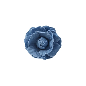 Top view of a blue denim camellia flower brooch with detailed fabric texture on white
