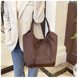 Close-up of brown faux suede tote bag with decorative bow and premium PU leather straps