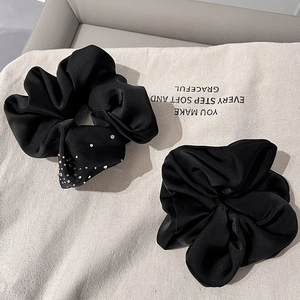 Elegant black satin hair scrunchies with rhinestones set on a decorative fabric bag