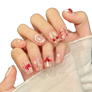 Red bow press-on nails with 3D cherry and mushroom designs on a translucent base