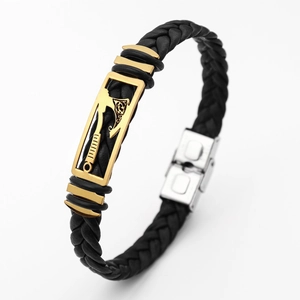 Detail of black woven leather bracelet with golden axe motif clasp and silver buckle