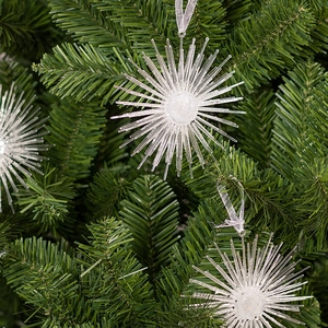 Sparkling champagne star burst acrylic ornaments hanging on a green Christmas tree