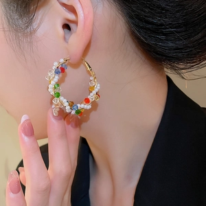 Macro detail of colorful crystal beaded hoop earrings on model with golden wire
