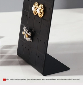 L-shaped black acrylic earring holder with 48 holes on white marble background
