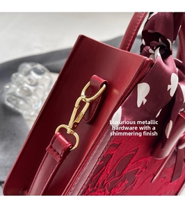 Detailed close-up of red floral embroidery and gold hardware on a bridal handbag