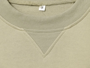 Détail de l'encolure d'un sweat en coton kaki avec étiquette de taille S cousue