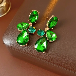 Macro shot of vintage teardrop earrings with green rhinestones in golden metal setting