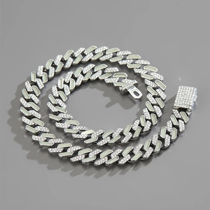 Close-up of a silver Cuban link chain necklace with sparkling rhinestones on grey background