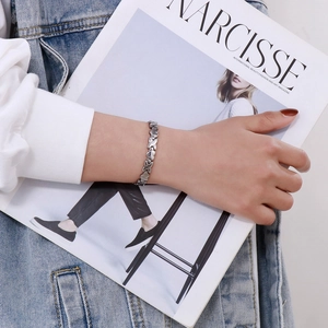 Detail of silver titanium heart and X-link bracelet worn against a fashion magazine