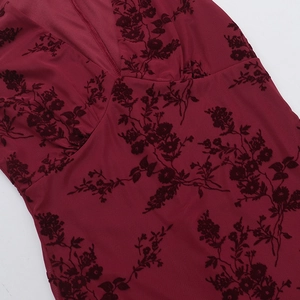 Detailed macro view of burgundy fabric with black flocked floral texture and V-neck stitching