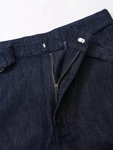 Détail de la taille d'un jean bleu foncé montrant la braguette zippée et les passants