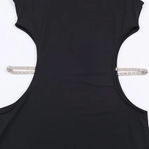 Détail de la taille évidée avec double chaîne de strass argentés sur une robe noire ajustée