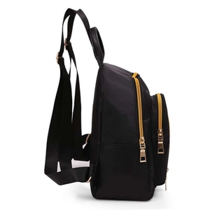Side view of black nylon backpack featuring gold zippers and multi-pocket structure