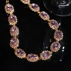 Macro detail of a pink gemstone necklace with sparkling crystals on gold plating