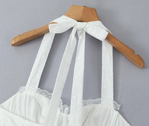 Détail de robe blanche en dentelle avec nœud papillon élégant et bordure fleurie délicate