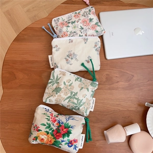 Flat lay of small floral cotton pouches with colorful pull cords on a wooden surface
