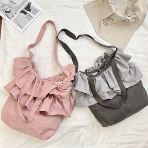 Flat lay of pink and grey ruffled shoulder bags with textured fabric in a lifestyle setting