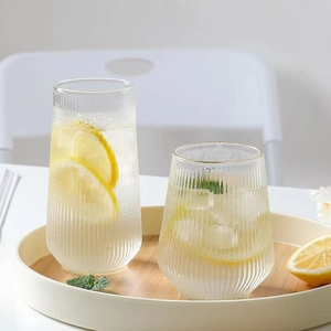 Tall and short vertical stripe glass cups with lemon drink on a wooden tray
