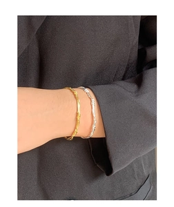 Macro view of gold and silver twisted vine bangles worn over a black blazer sleeve