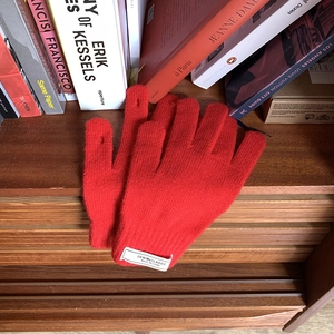 Detail of red knit touchscreen gloves on rustic wood surface with cozy lifestyle background