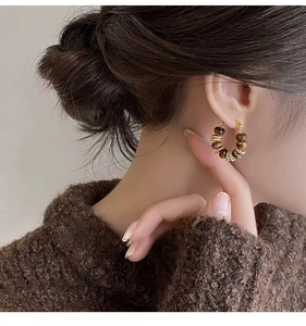 Detail of vintage tiger eye beaded hoop earrings worn by a model in soft lighting
