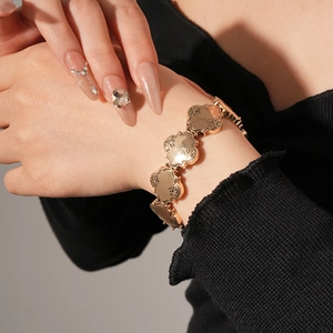 Détail d'un bracelet en métal doré avec des motifs floraux en relief portés au poignet