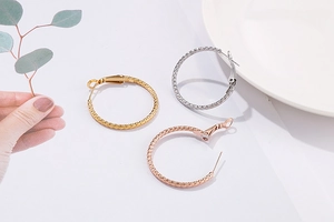 Detail of metal hoop earrings with woven texture in gold, silver and rose gold colors