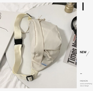 Close-up of cream canvas chest bag showing adjustable strap and buckle detail