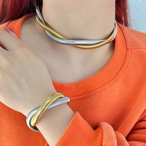 Detail of two-tone gold and silver twisted snake chain necklace and bracelet set on model