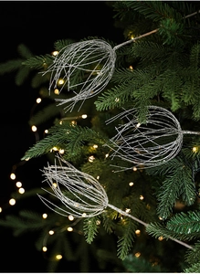 Gros plan d'ornements en branches argentées scintillantes sur un sapin de Noël illuminé