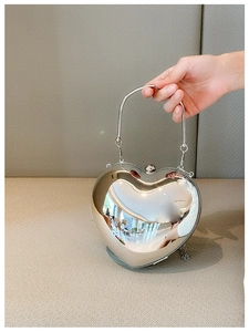 Macro view of silver mirror acrylic heart-shaped handbag with metallic chain handle