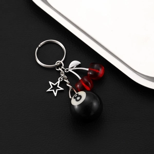 Detail of cherry keychain with number 8 billiard ball and silver star on black leather