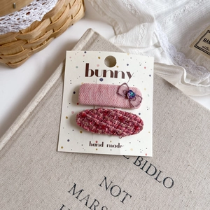 Detailed macro view of pink fabric bow hair clips with purple crystal on branded display card