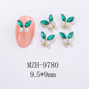 Detailed view of green butterfly nail charms with rhinestones and pearls on pink nail tip