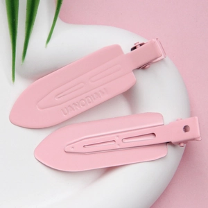 Close-up of pink non-marking hair clips with brand engraving on white heart plate