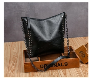 Detail of black PU leather shoulder bag with rivet accents and metal chain strap