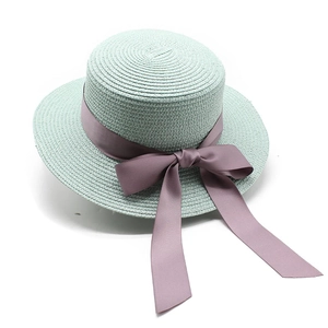 Détail d'un chapeau de paille vert menthe avec un ruban et un nœud en soie lavande